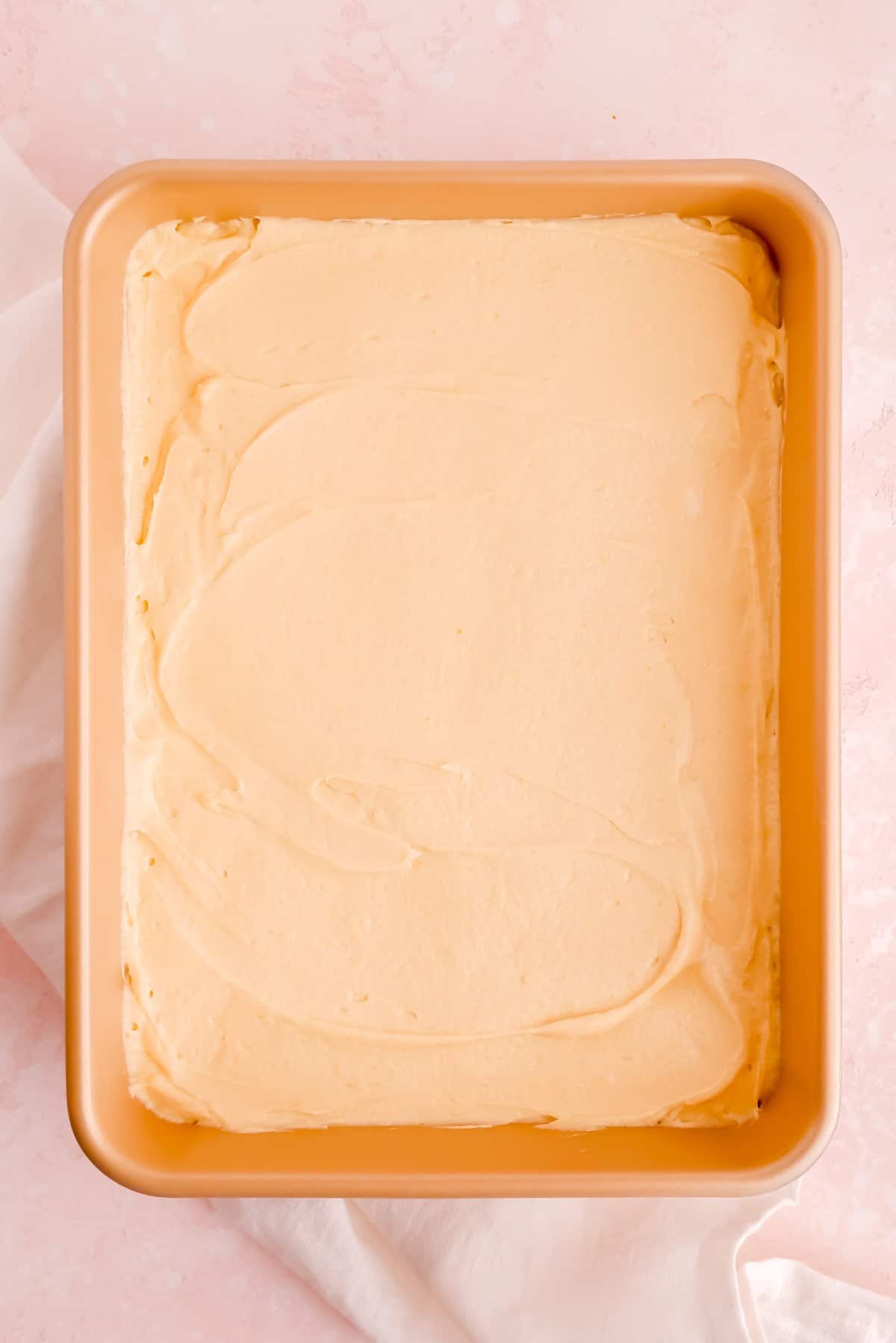 Vanilla sheet cake batter spread evenly in a gold 9 x 13 pan.