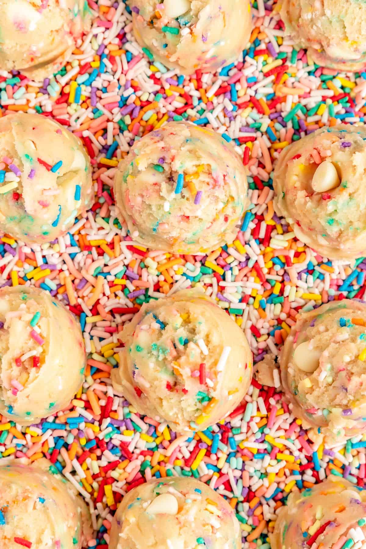Close up of cookie dough scoops from overhead on background of sprinkles.
