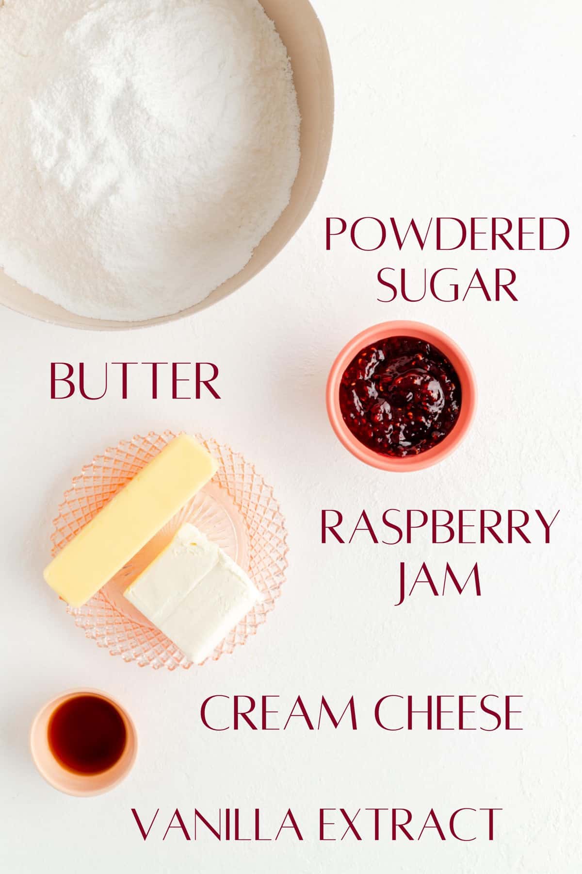 Ingredients for raspberry cream cheese frosting in individual bowls on white background.