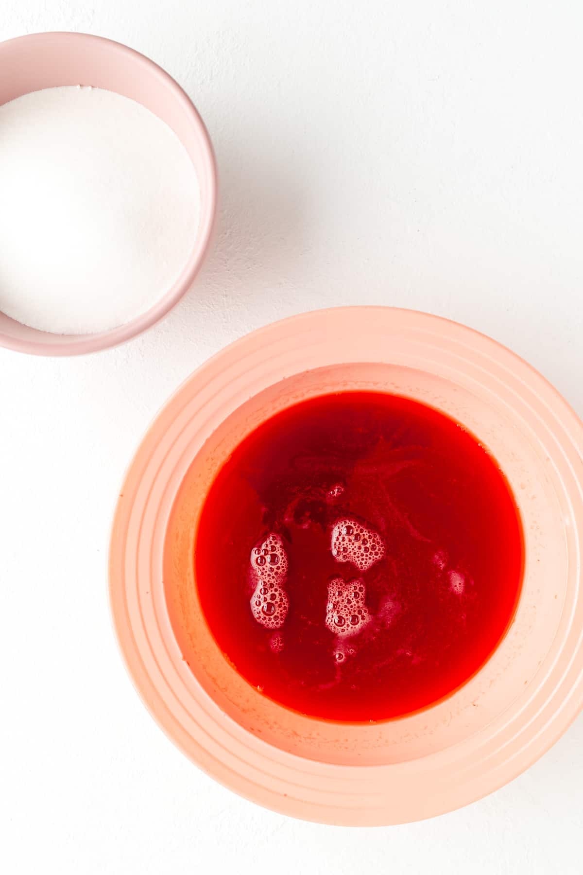 Overhead shot of pink ball with strawberry water and another bowl with sugar.