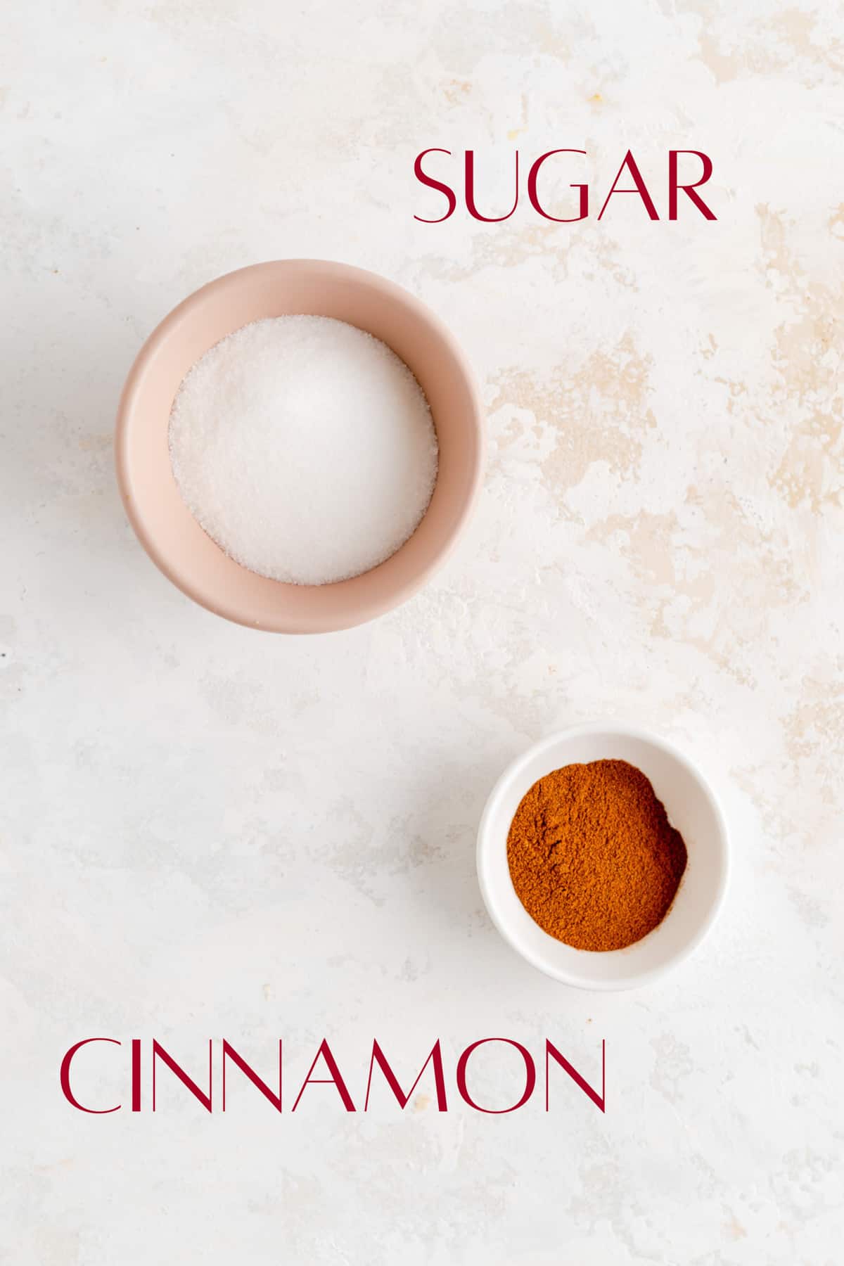 sugar and cinnamon in individual bowls on white plaster background.