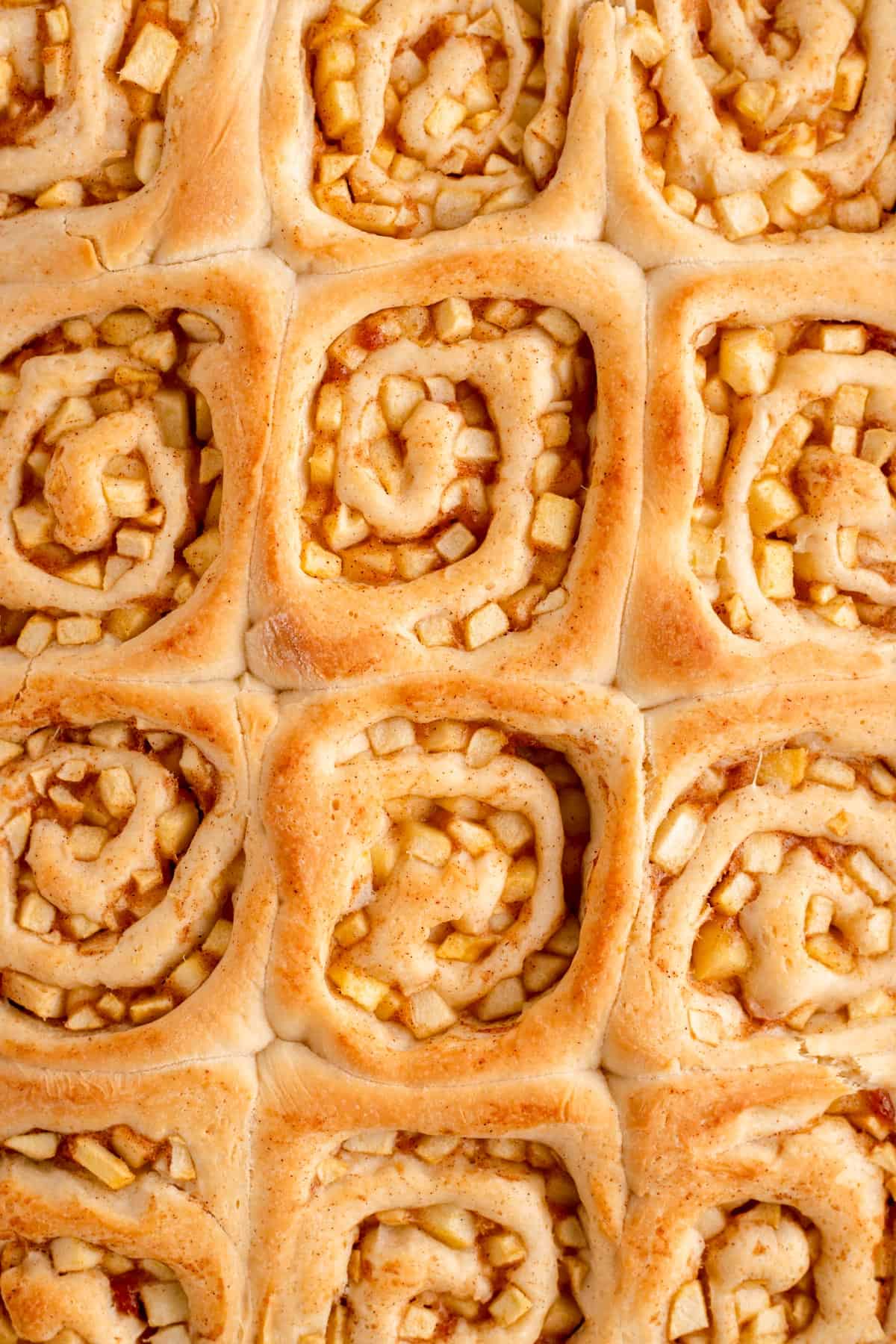 overhead close up of apple-filled cinnamon rolls still in their pan.