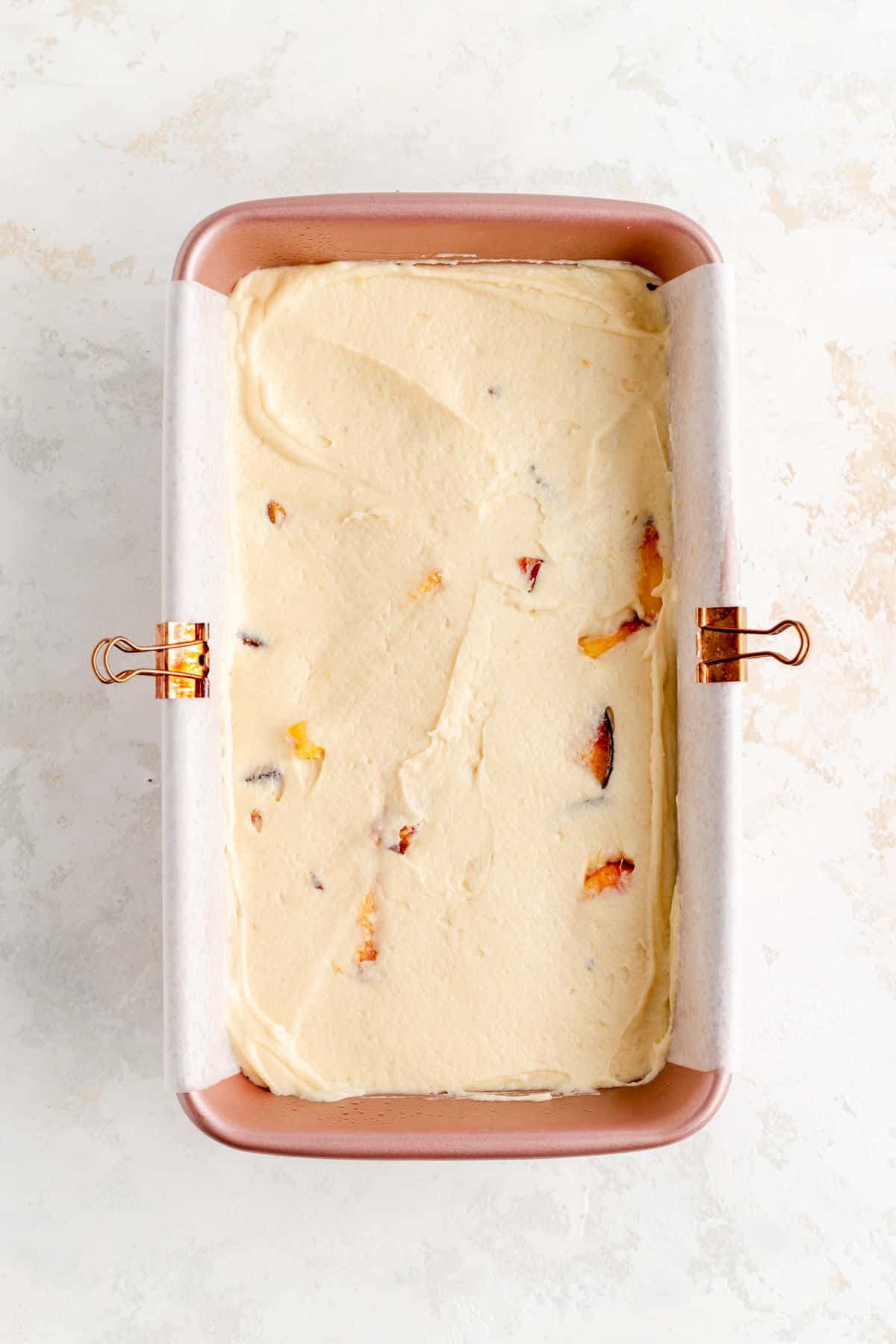 peach cobbler pound cake batter spread evenly in parchment-lined pink loaf pan.