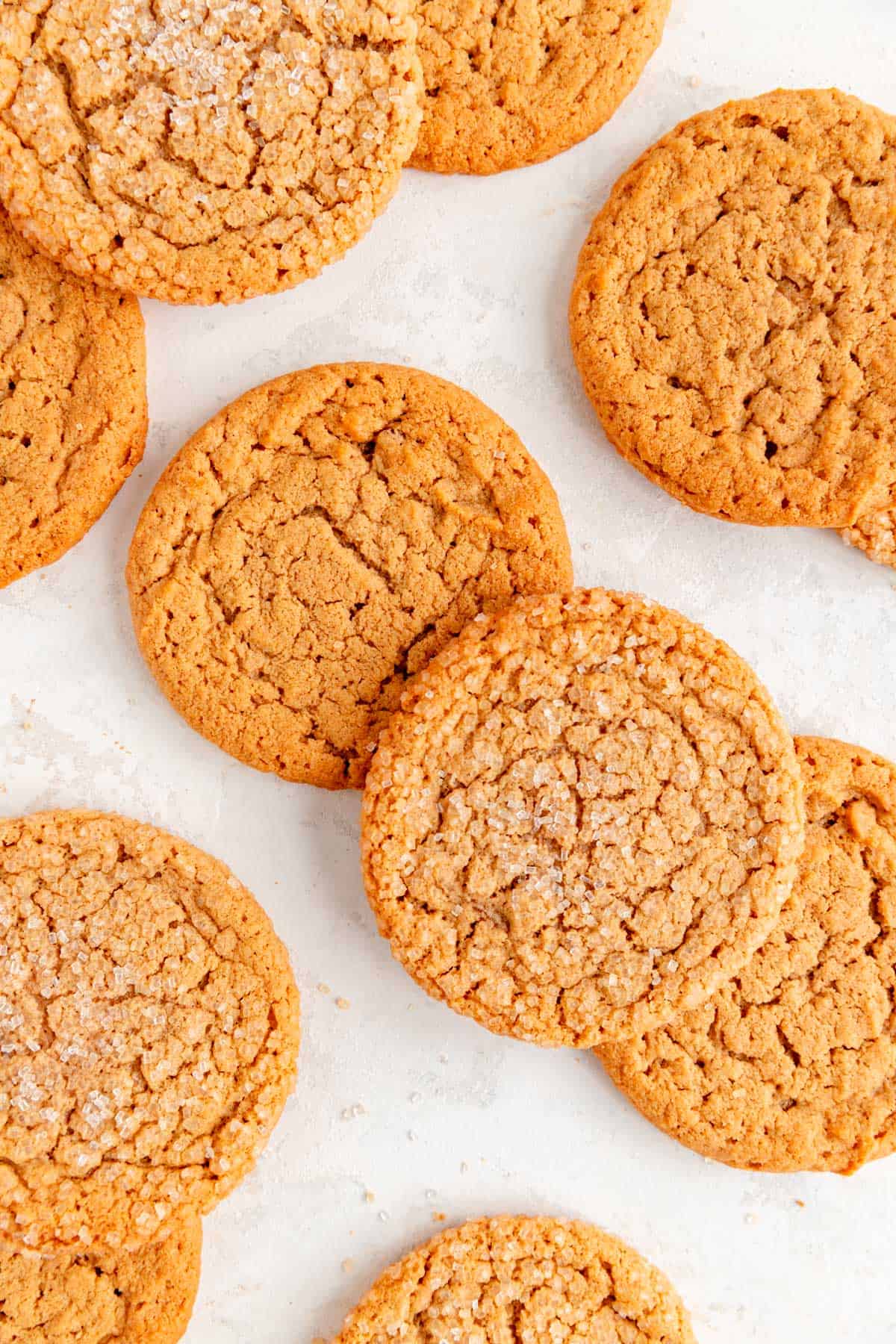 gluten free peanut butter cookies with and without sugar coating stack on white plaster background.