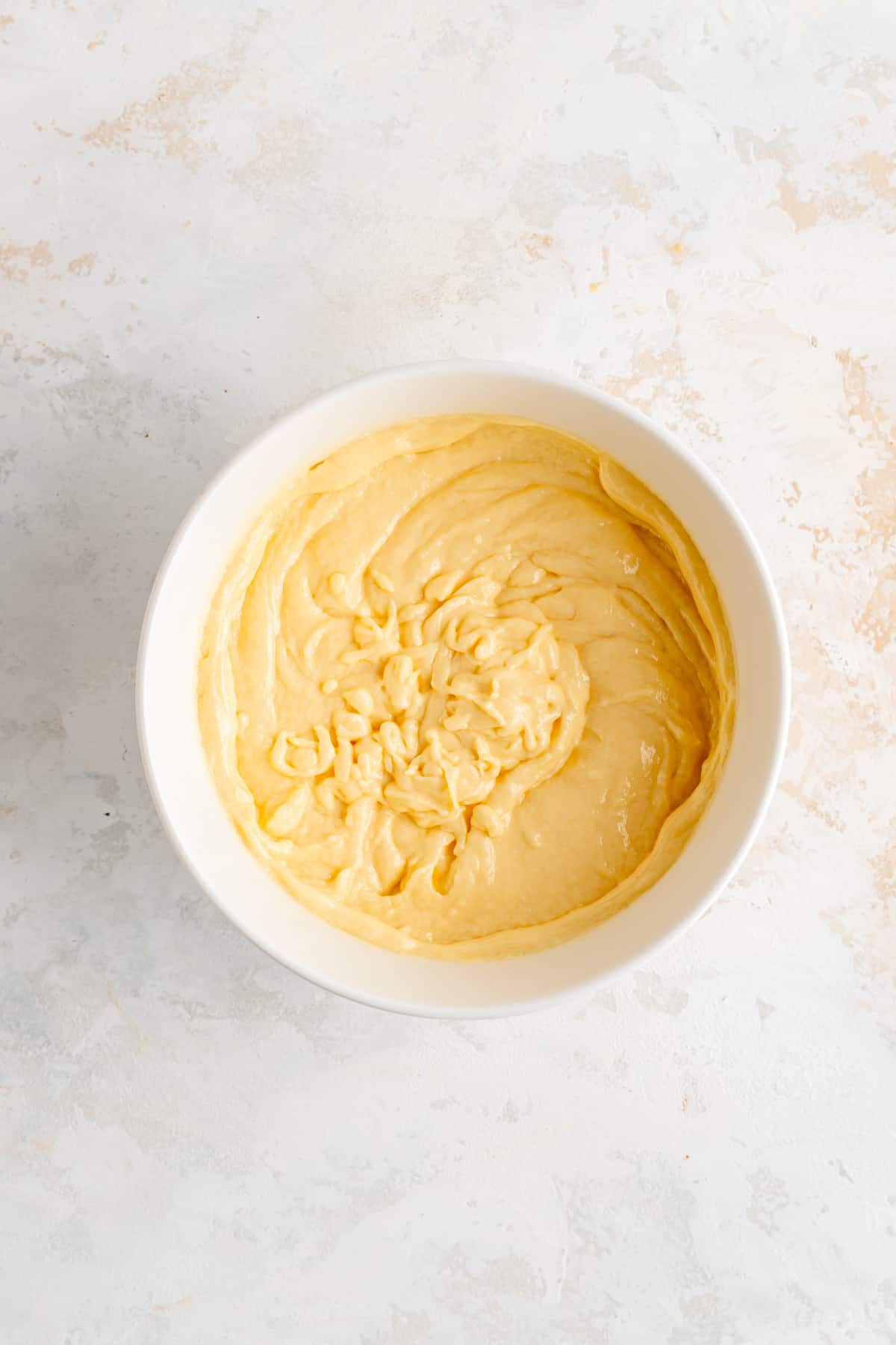 Mixed wet ingredients in white bowl on white background.