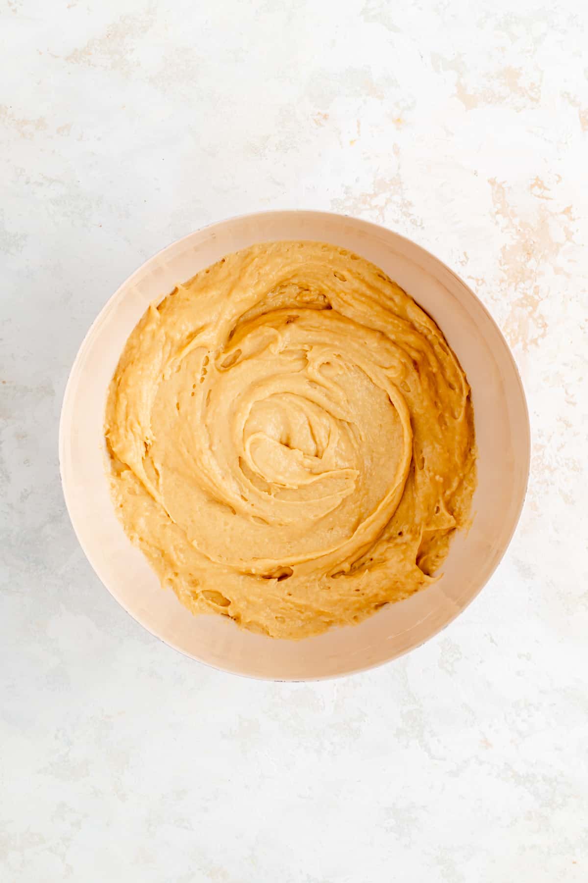 Plain brown sugar sour cream raw muffin batter in tan bowl on white background.