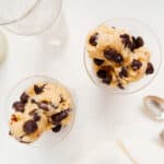 Two small glasses filled with scoops of edible chocolate chip cookie dough on white background.