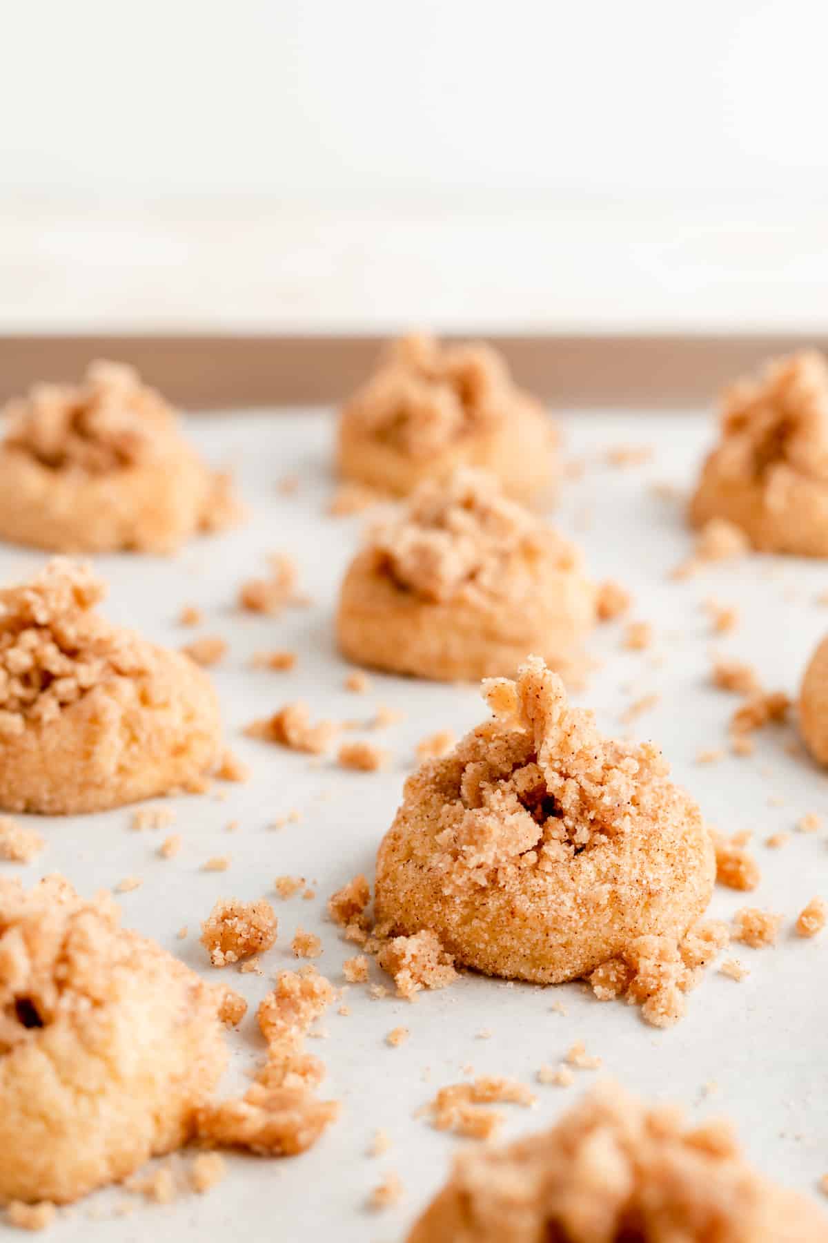 side angle of streusel piled on thumbprinted cookies on tan tray.