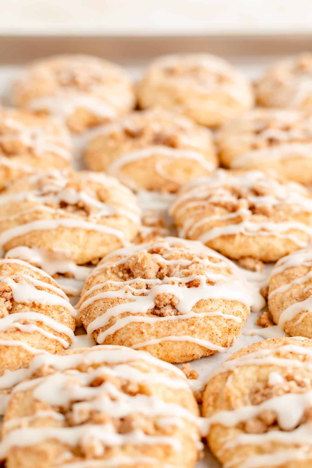 45 degree angle close up of icing drizzled coffee cake cookies on baking tray.