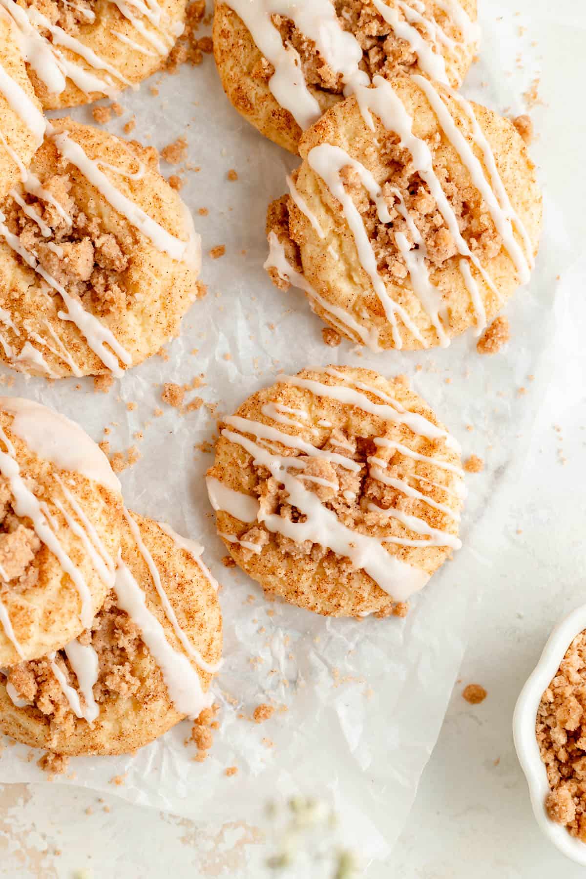 overhead of coffee cake cookies on white parchment with bowl of streusel in the corner.