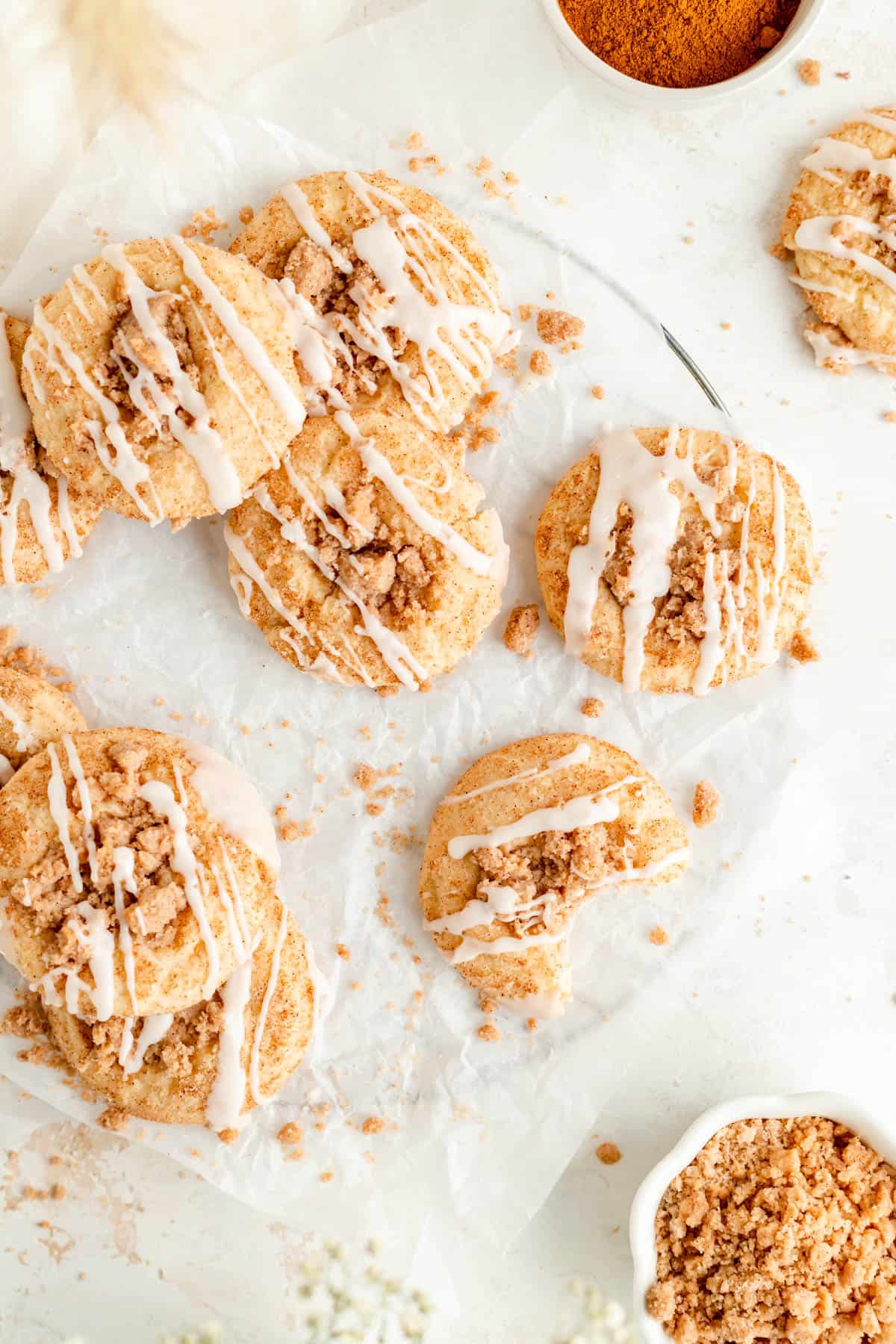 overhead of coffee cake cookies stacked on white parchment with bite out of one cookie.