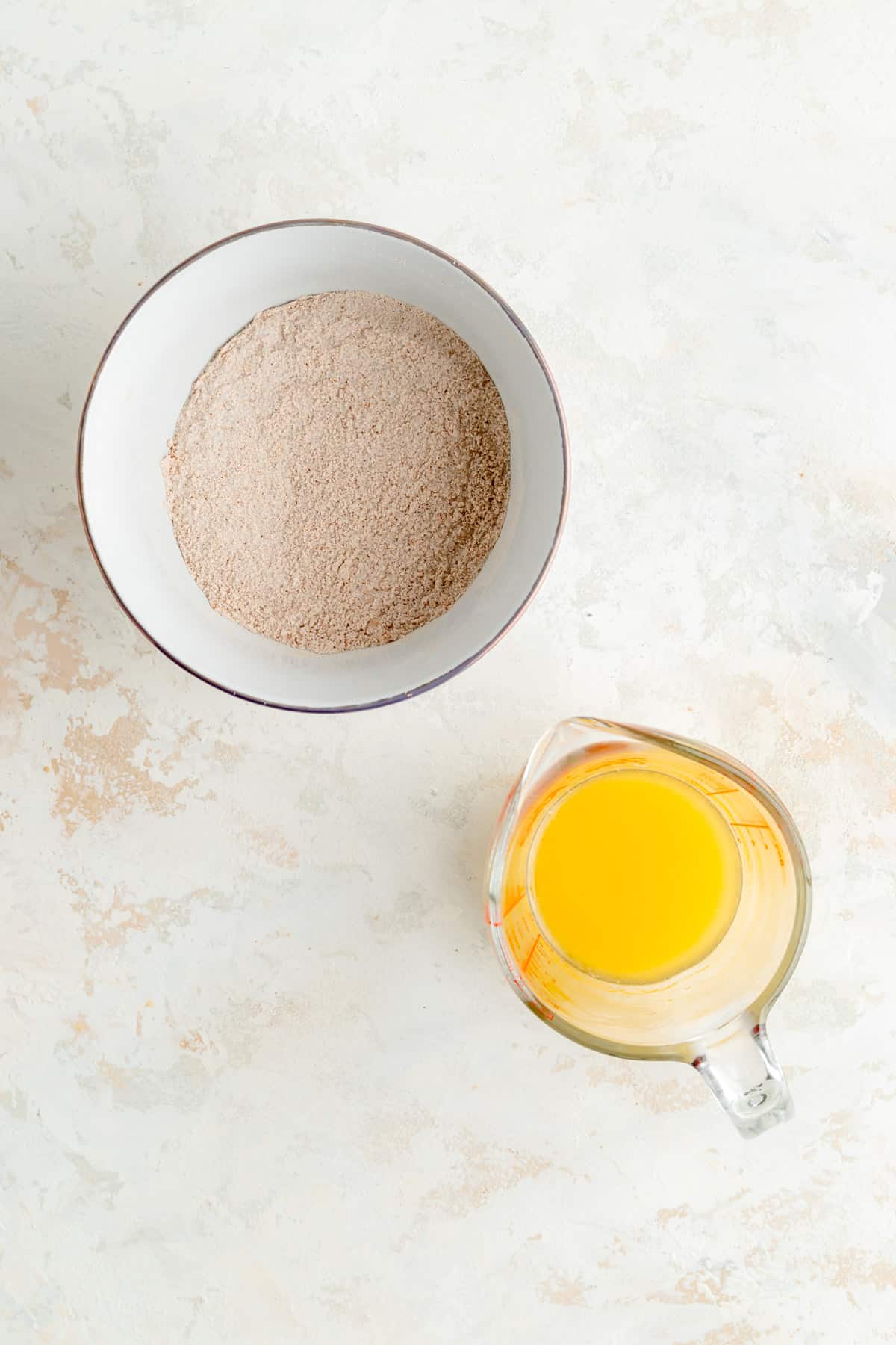 a bowl of streusel dry ingredients and a glass pitcher of melted butter.