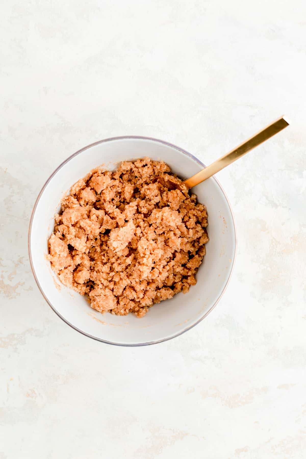 cinnamon streusel in a white cowl with a gold fork on white background.