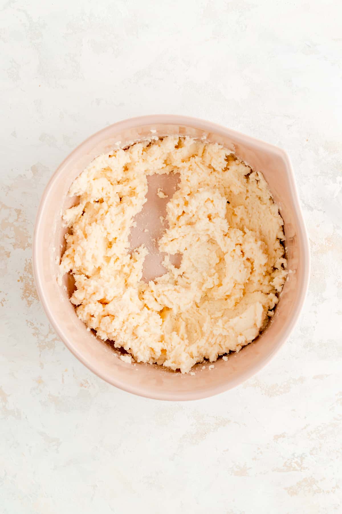creamed butter and sugar in a tan bowl on white background.