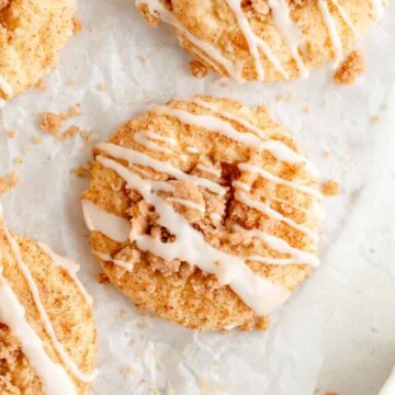 overhead of coffee cake cookies on white parchment with bowl of streusel in the corner.