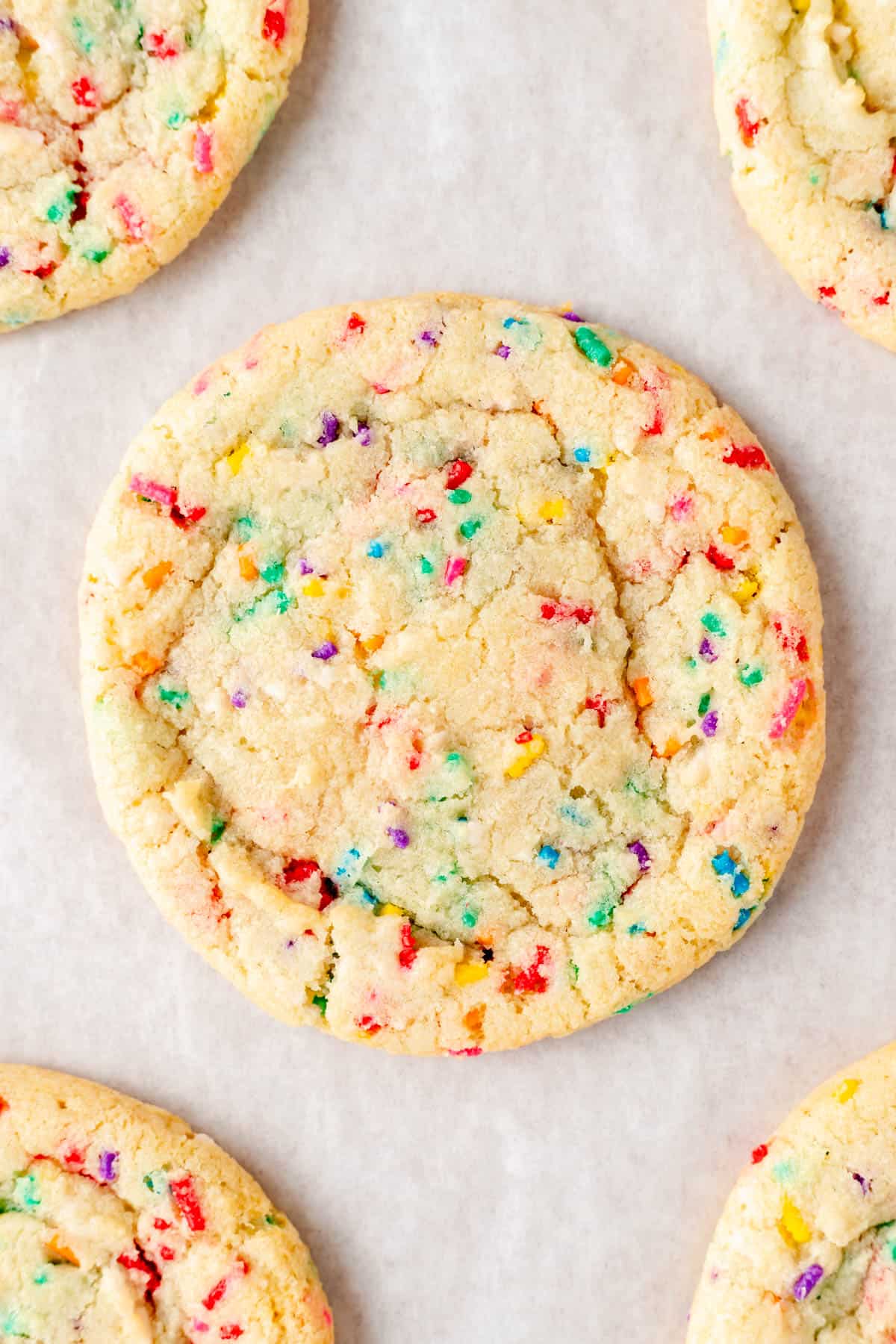 Close up of funfetti cookie on parchment paper with other cookies around.