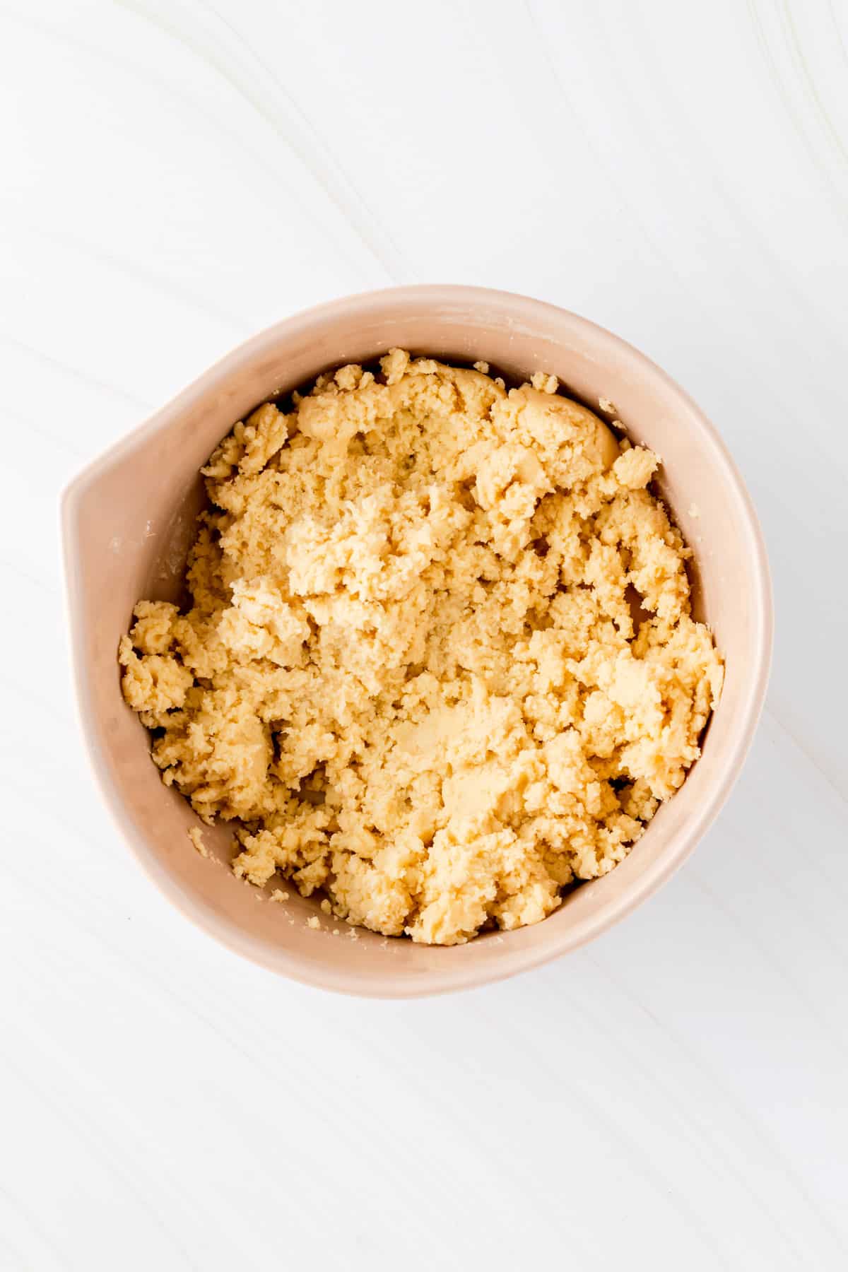 funfetti cookie dough mixed in a tan mixing bowl on white background.