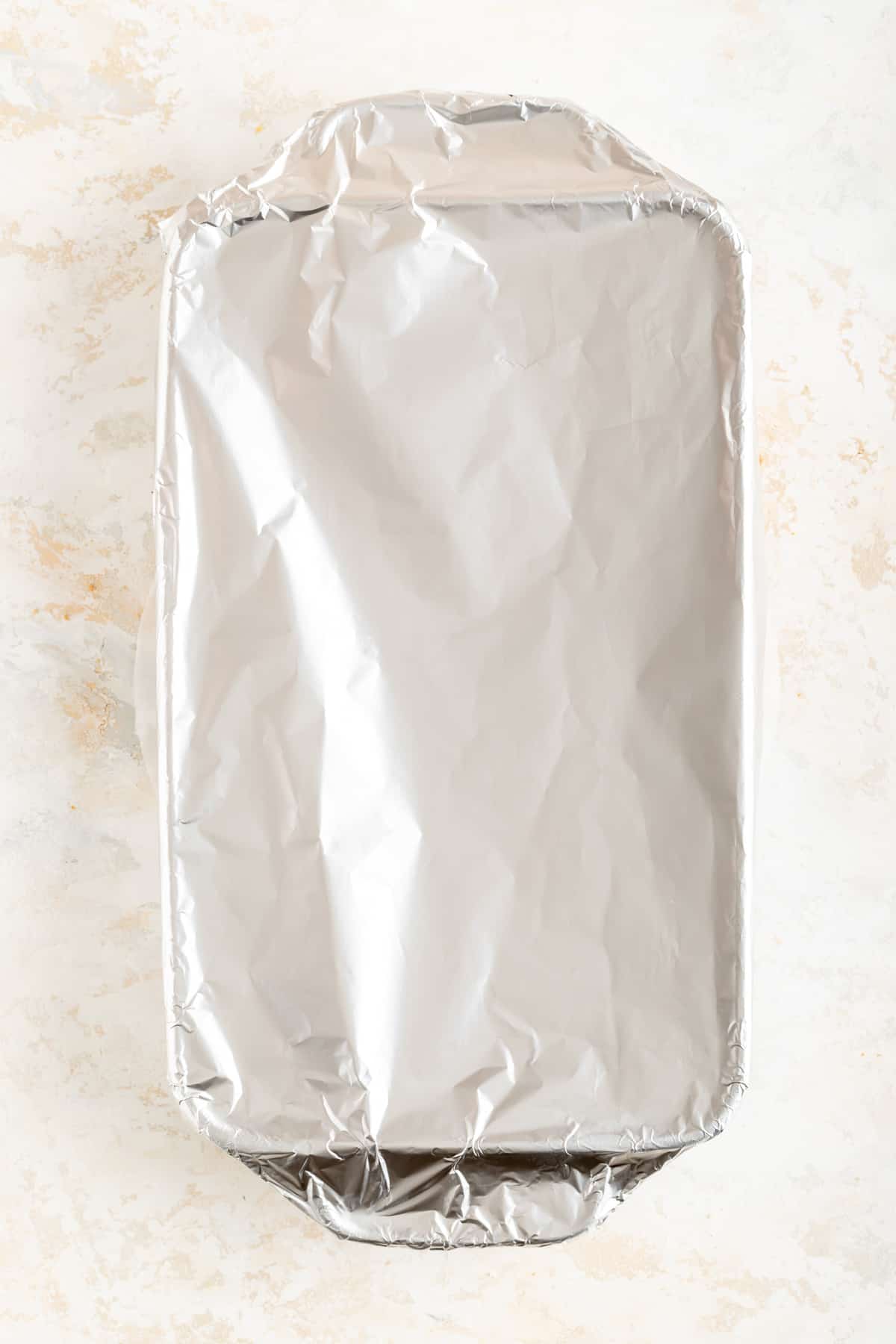 foil covered rectangular pan on a white plaster background.