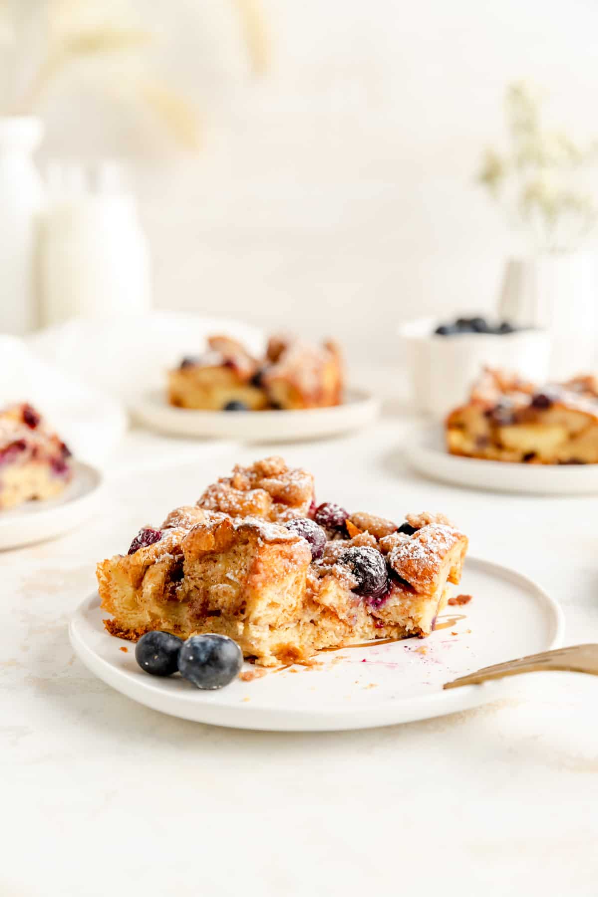 side view of a pieces of brioche french toast casserole with blueberries with a bite out.