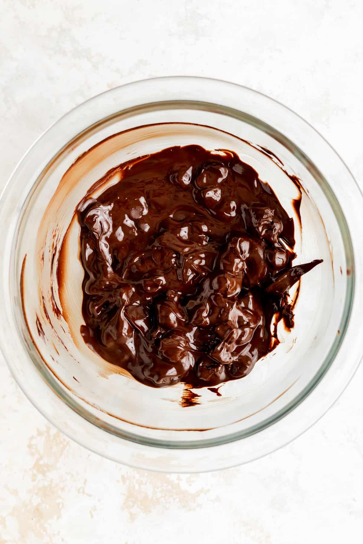 overhead view of partially melted chocolate chips in a glass bowl after 1 minute of microwaving.