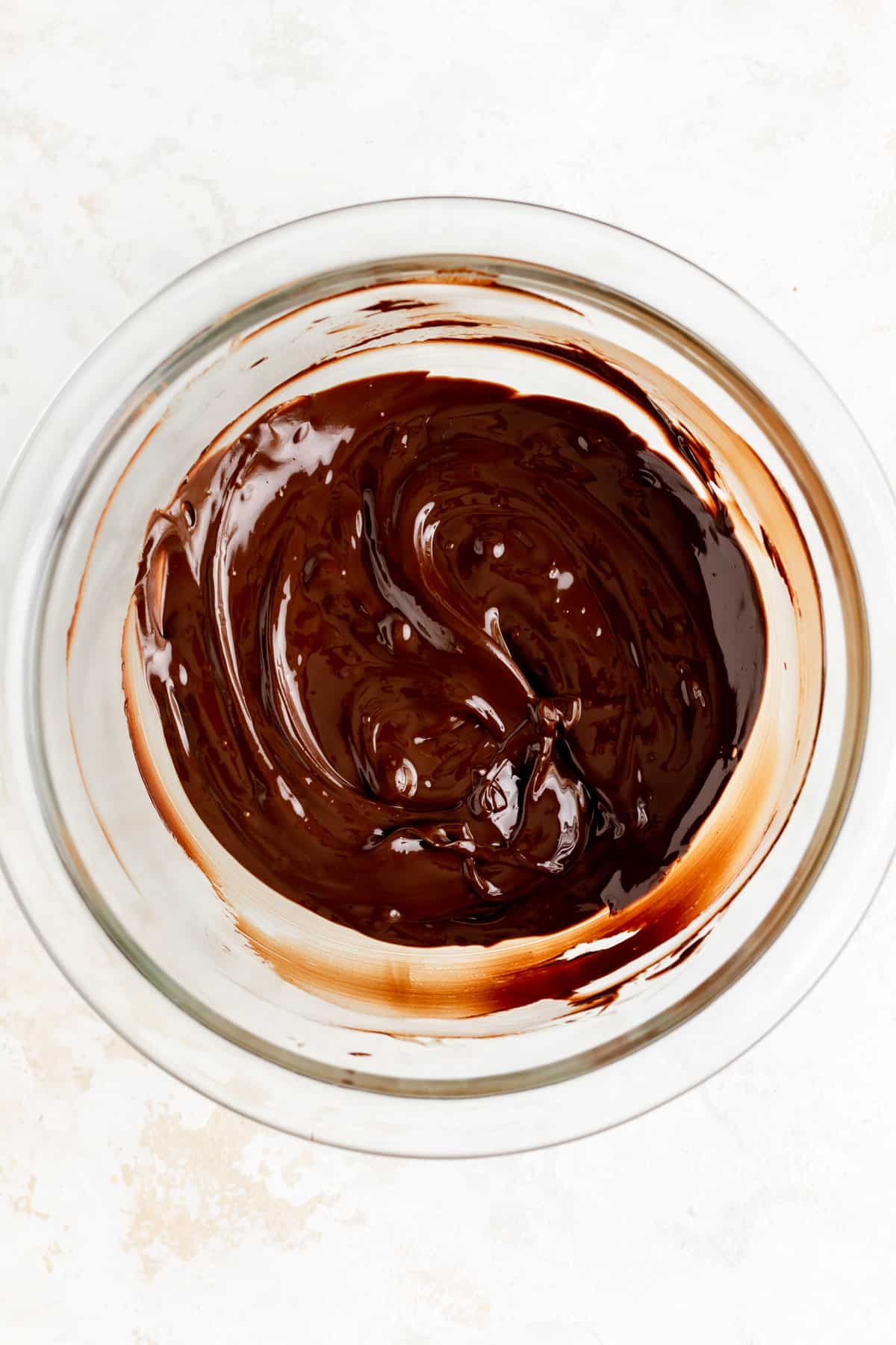 overhead view of melted chocolate in a glass bowl after 70 seconds of microwaving.