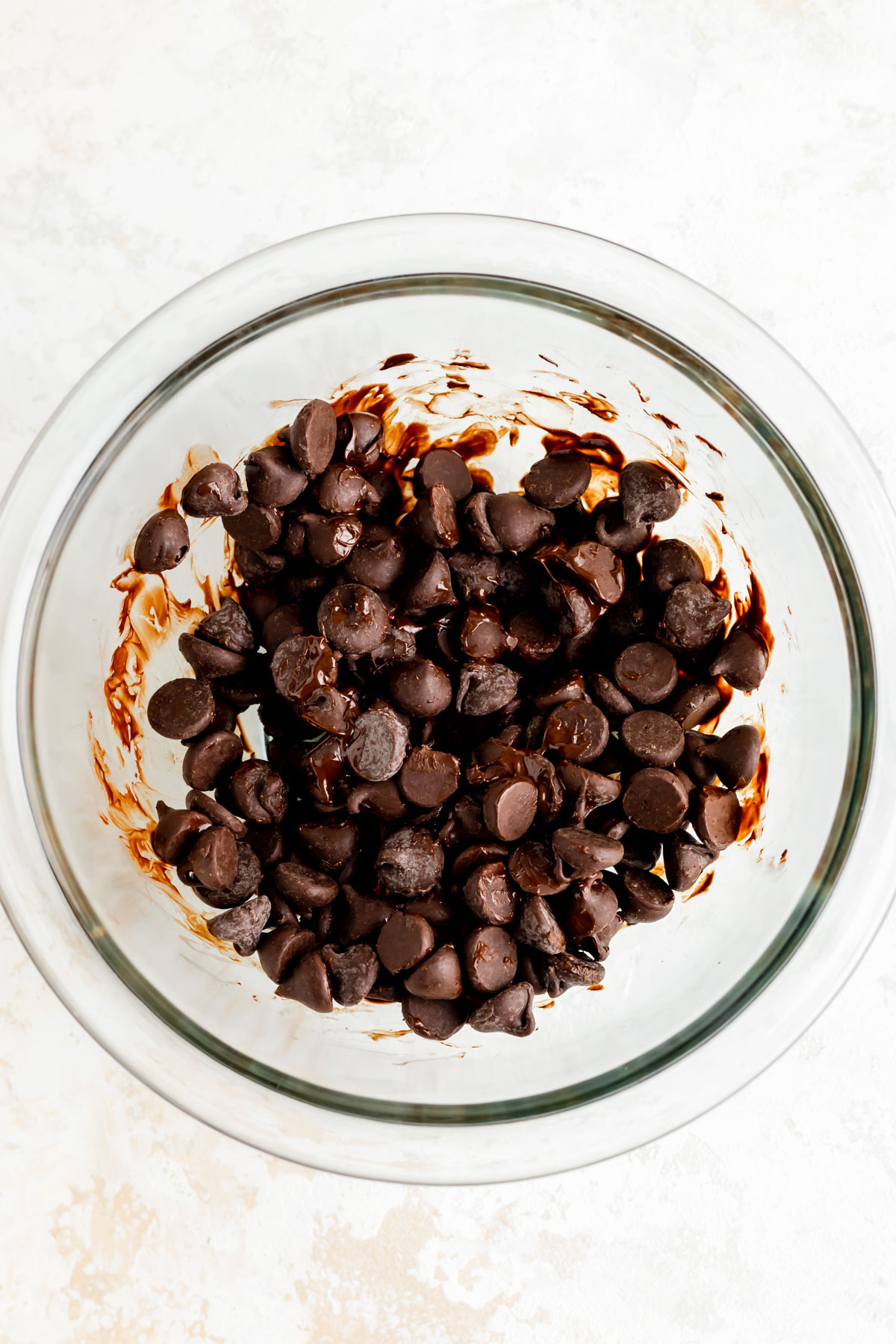 overhead view of chocolate chips in a glass bowl after 30 seconds of microwaving.