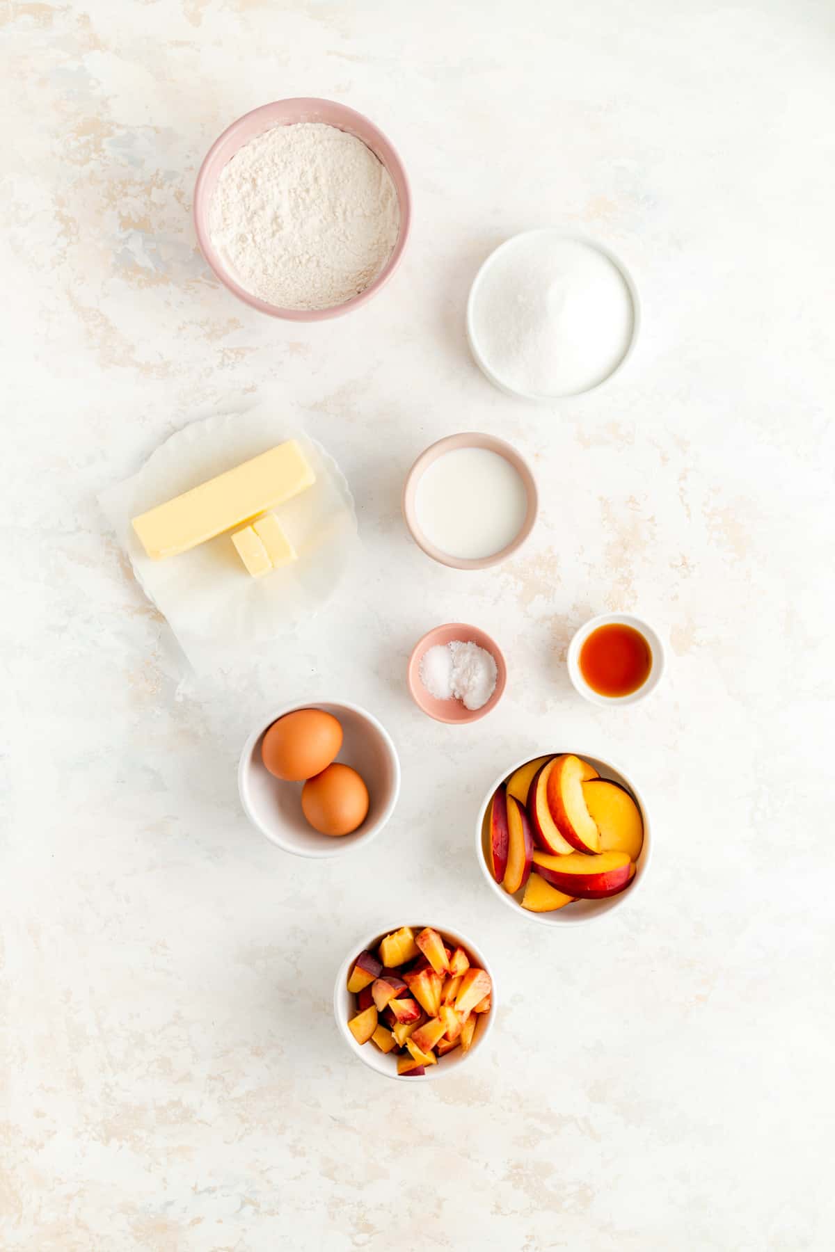 ingredients for peach pound cake in individual bowls on white background.