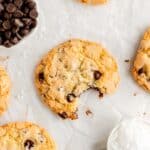 chocolate chip cookie with bite out from above surrounded by other cookies and ingredient bowls