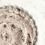 close up of swirled cookies and cream frosting in a white scalloped-edged bowl.
